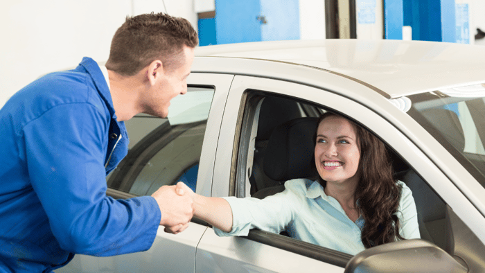 Cliente feliz de un taller de coches estrechando la mano de un mecánico