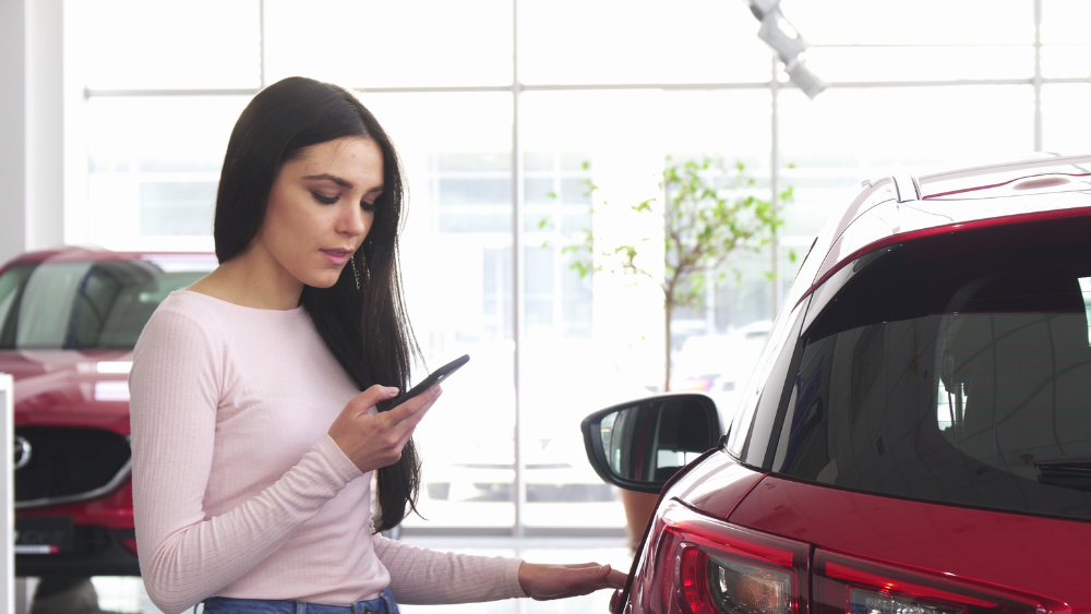 Woman with mobile in car dealership