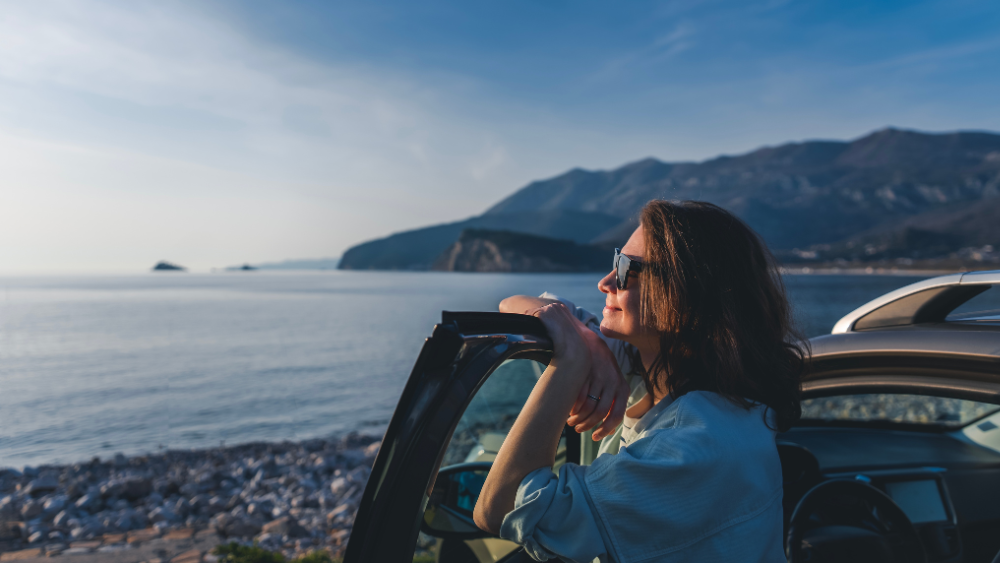 Female tourist looking at landscape with rental car