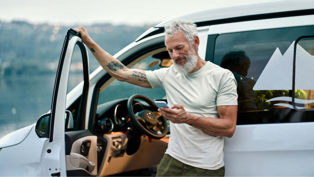 Mature man with smart phone and car 