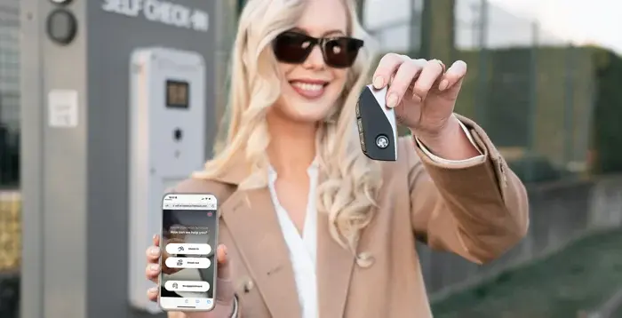Femme avec un smartphone et une clé devant une Sharebox