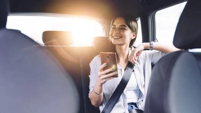 Young woman in back of car with smartphone